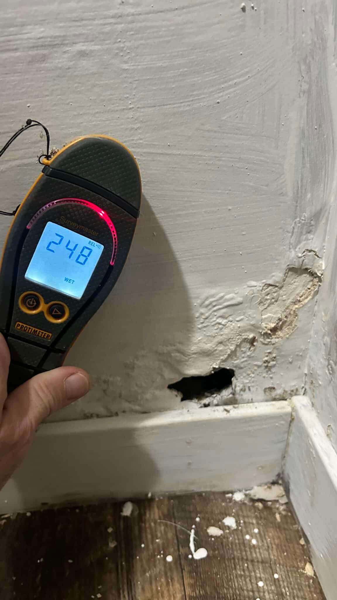 Moisture measurement beside a damaged wall and baseboard